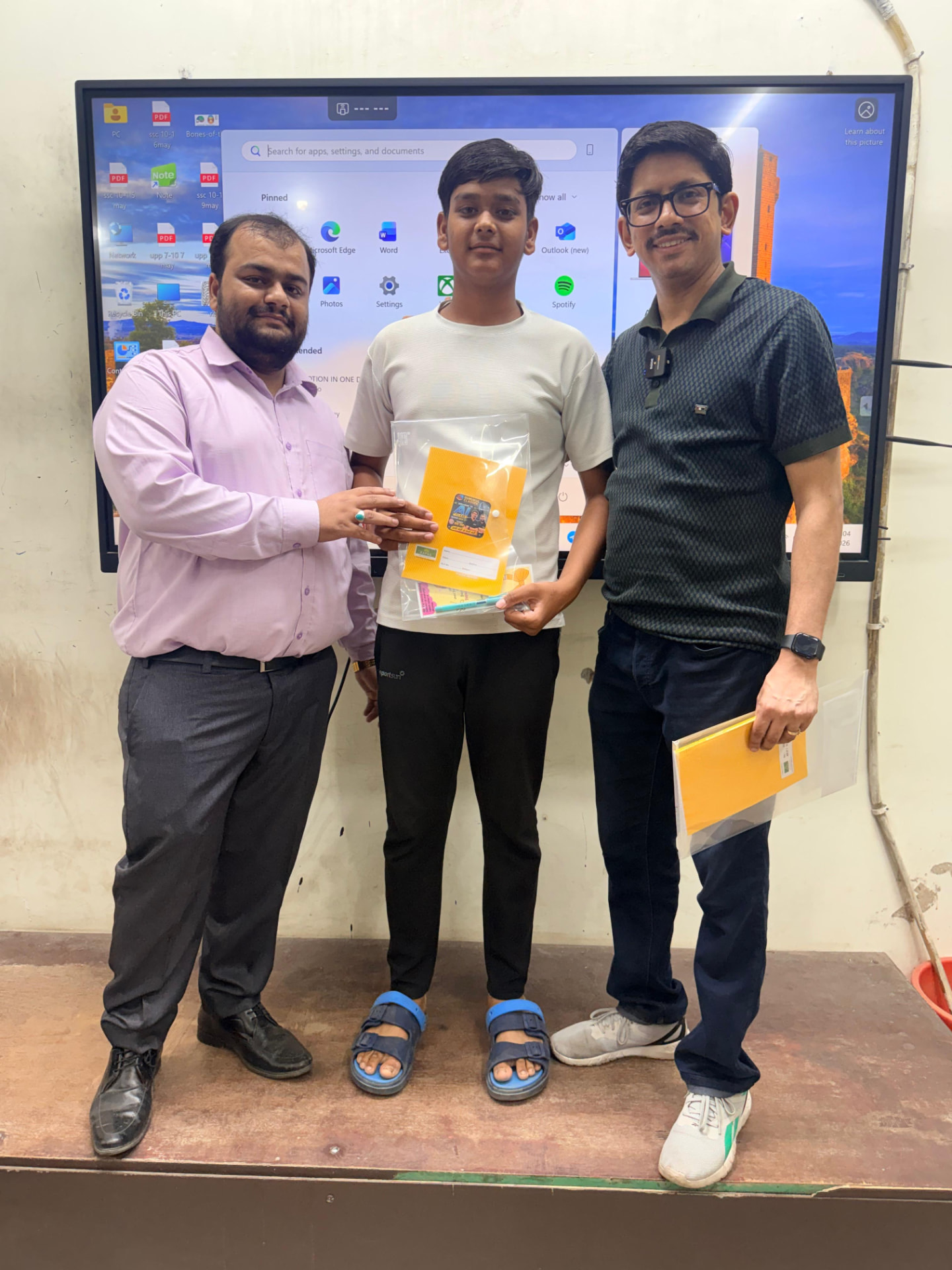 Student receiving a Gurukul Classes study kit from faculty at the smart-board classroom