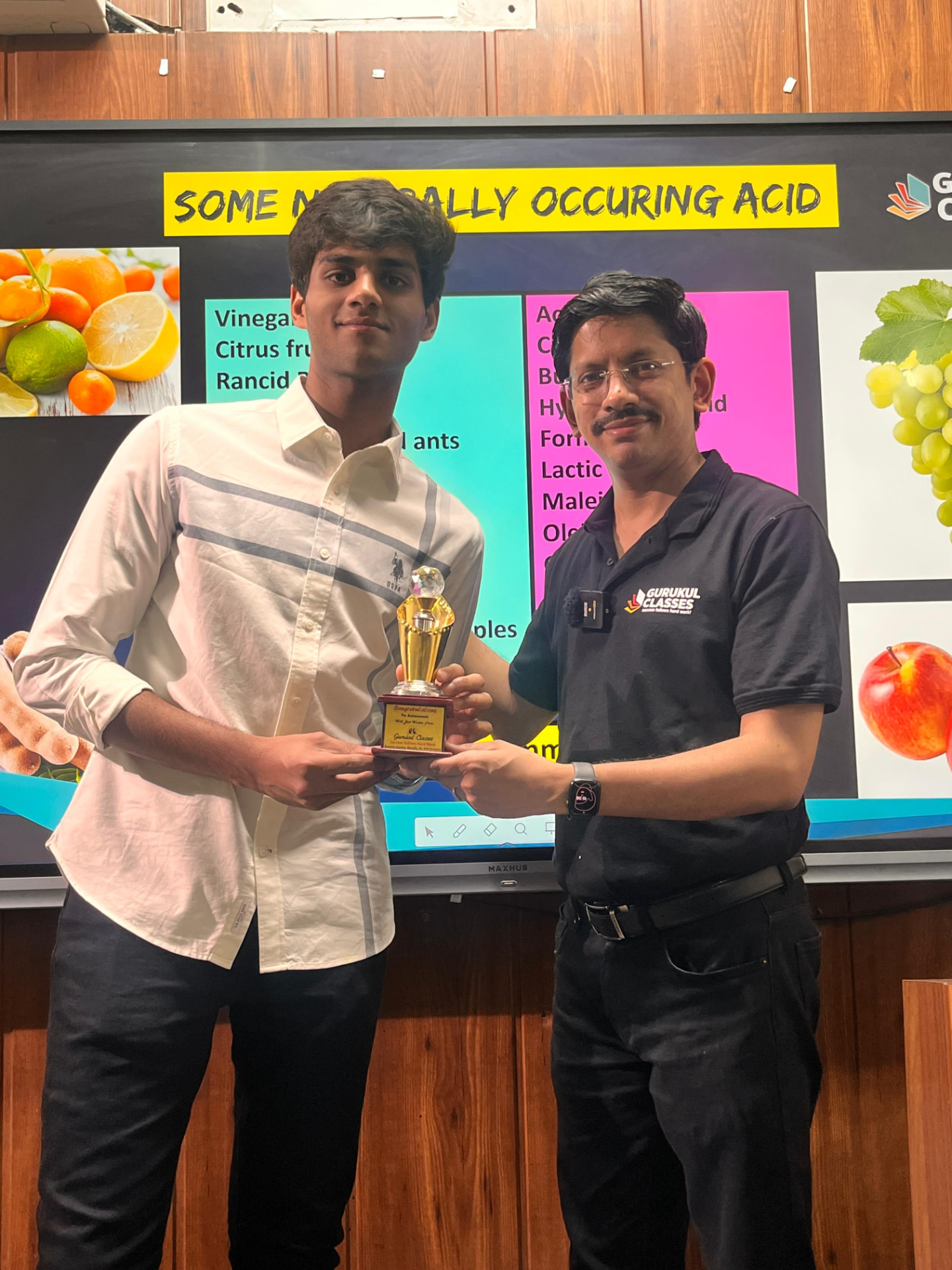 Student receiving an achievement trophy from Vaibhav Agarwal at Gurukul Classes