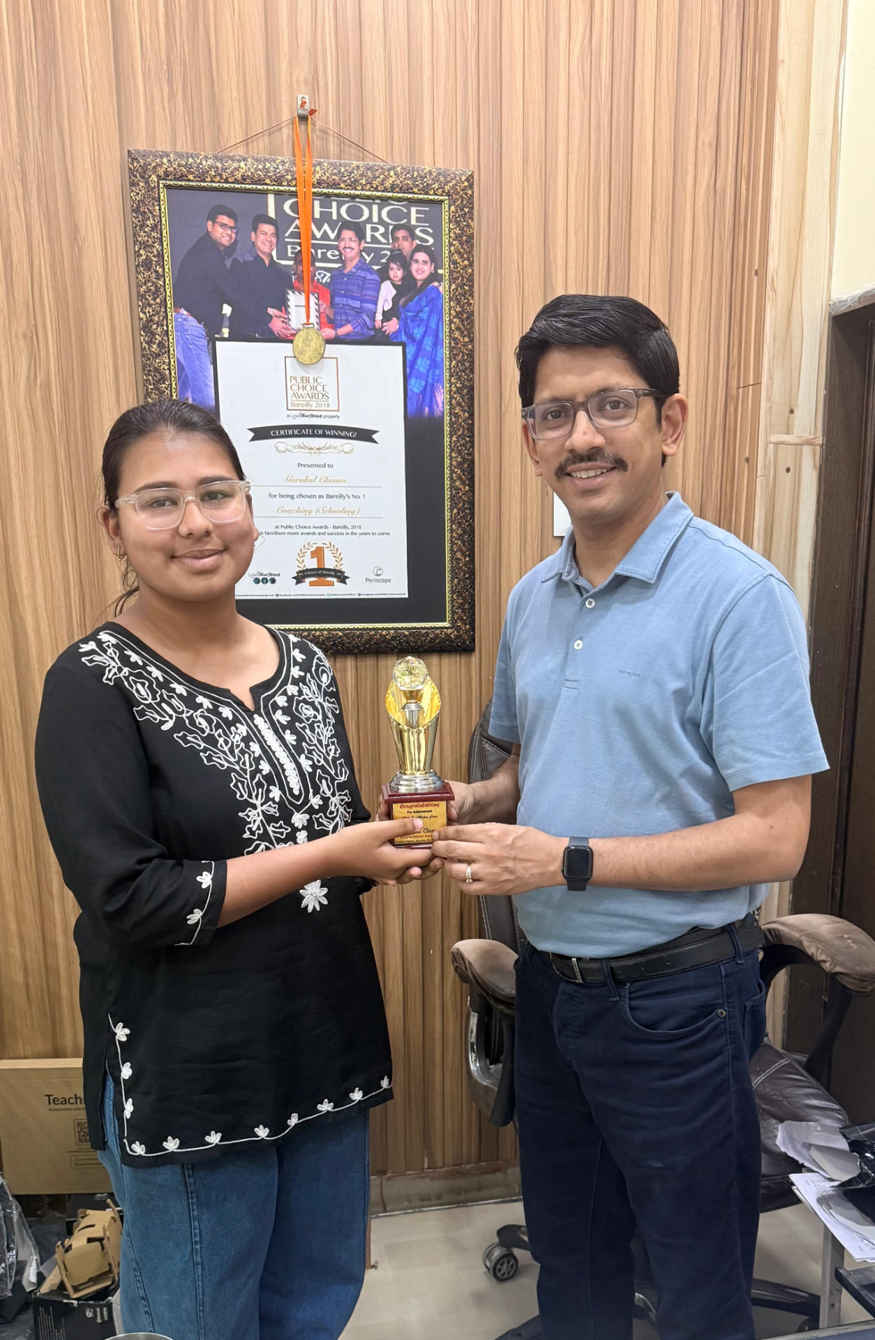 Student receiving an achievement trophy from Vaibhav Agarwal at the Gurukul Classes office