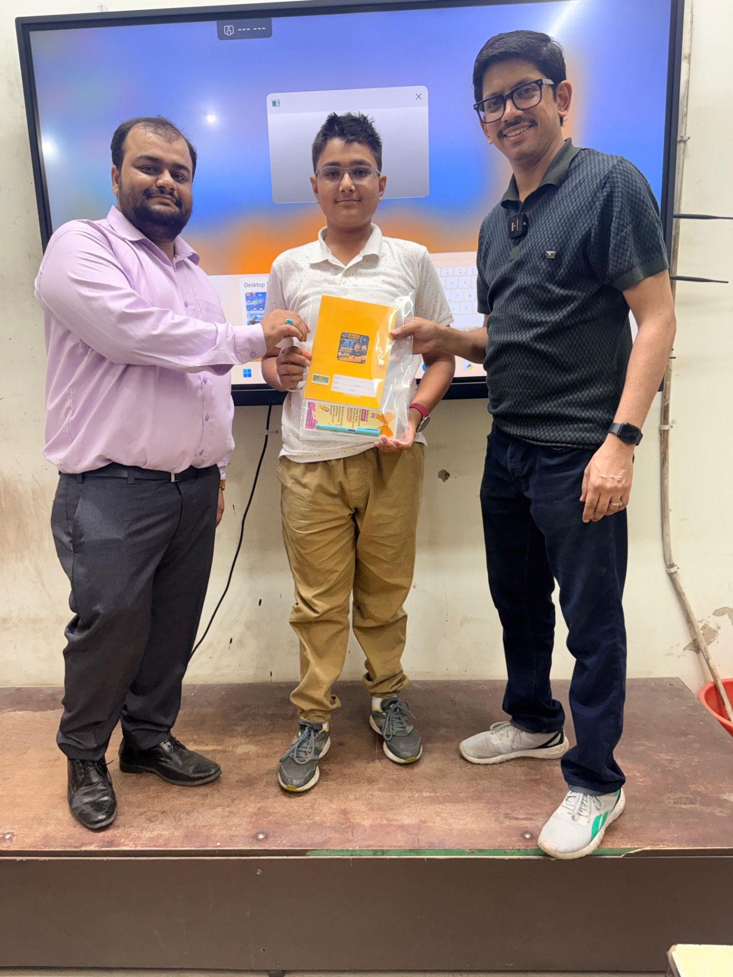 Student receiving a Gurukul Classes practice booklet kit from two faculty members