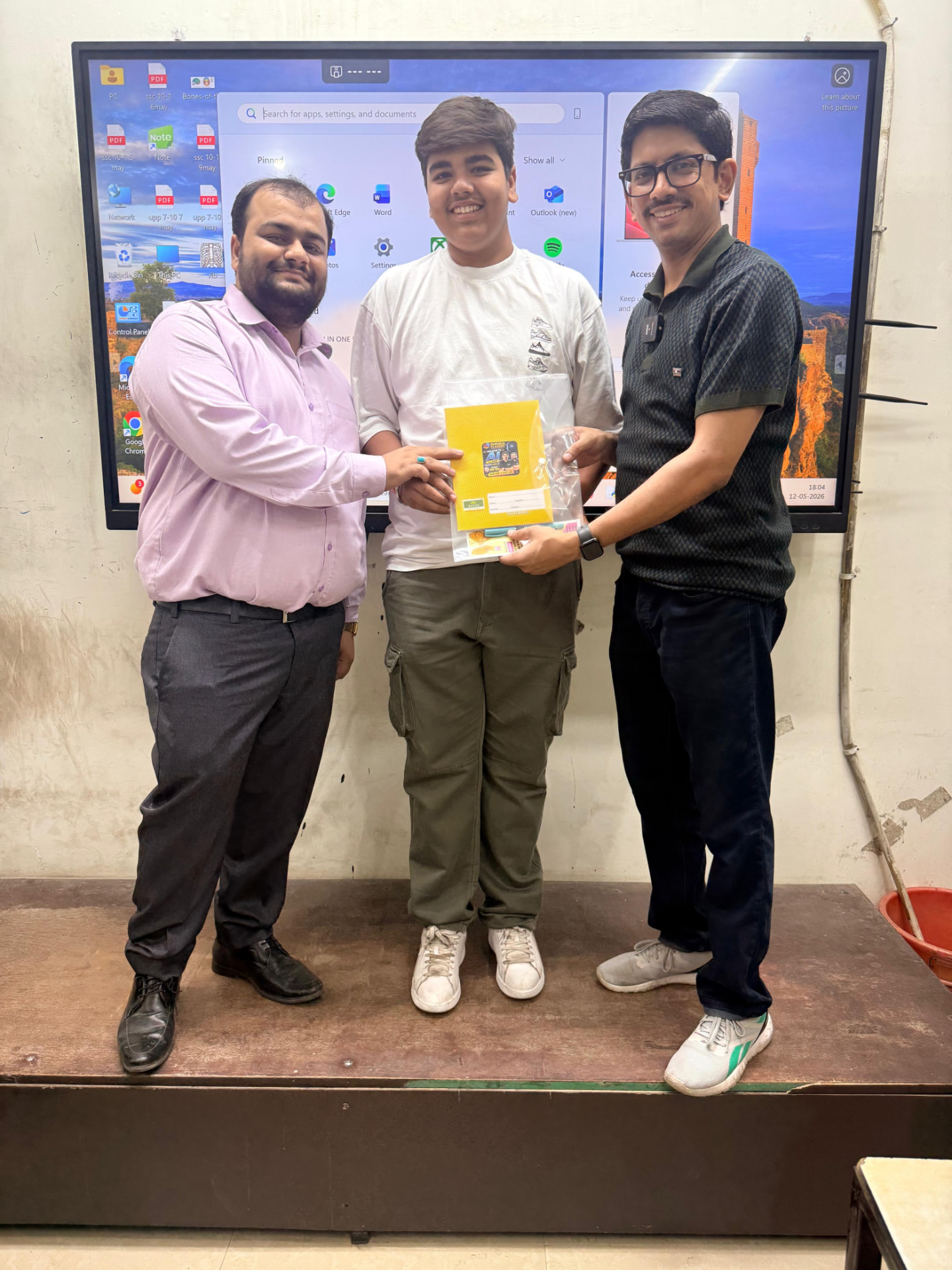 Smiling student handed a Gurukul Classes study kit by faculty