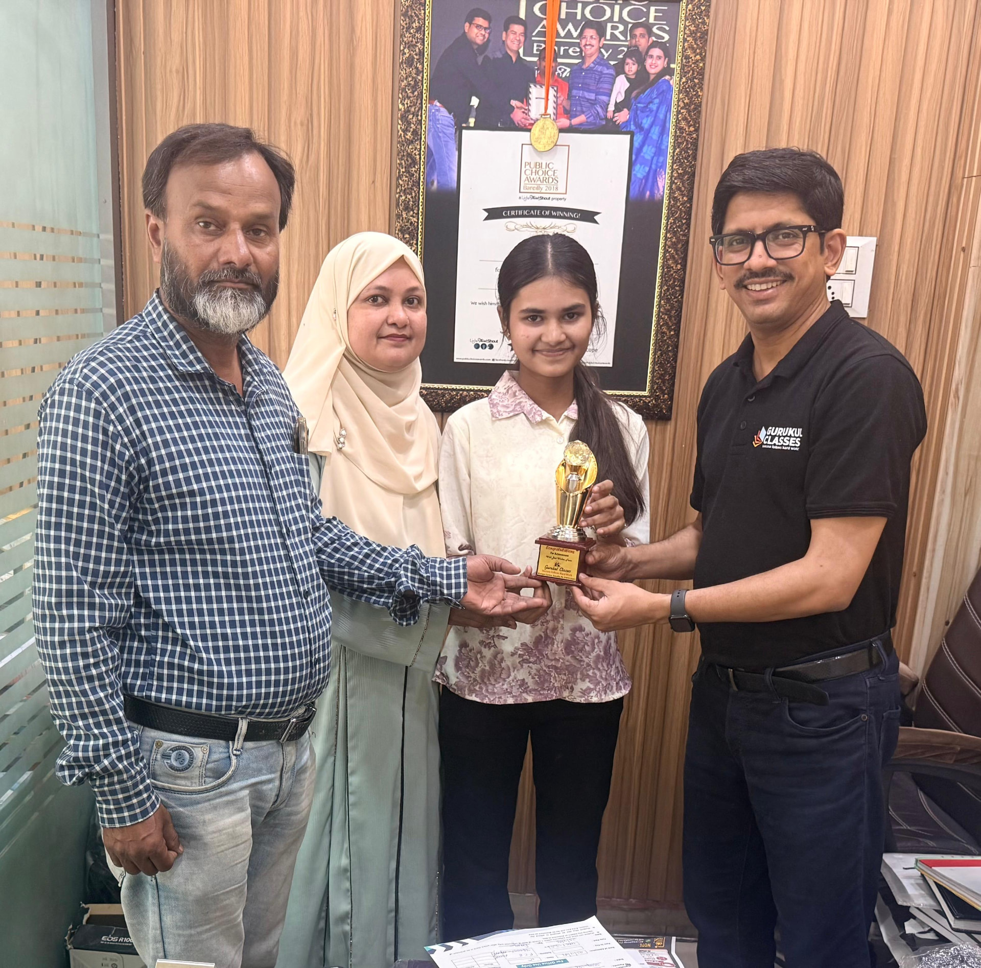 Parents and student felicitated with a Gurukul Classes achievement trophy